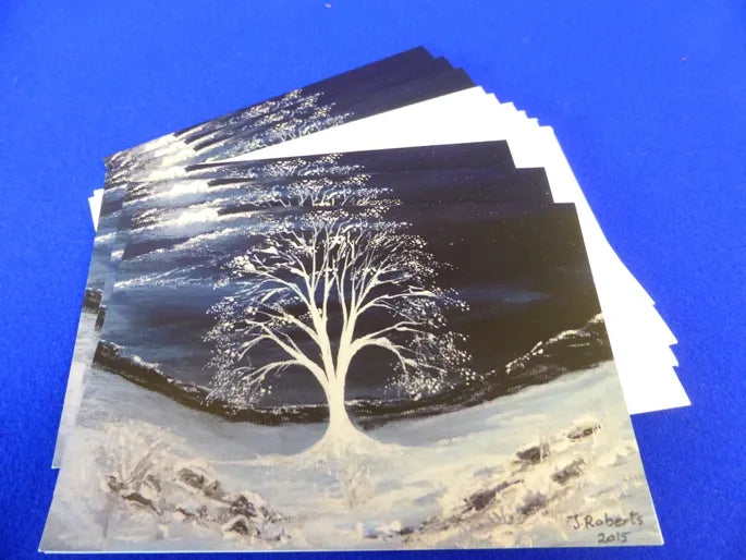 Christmas Cards, Pack of 6 White Moonlit Sycamore
Print of an original artwork by Joanne Roberts, Unique view of sycamore gap tree on Hadrians Wall in winter, in Northumberland, UK. Tree is painted white in the centre and set on a deep dark blue winter sky with the moon peeping through the clouds on the top left. Pack of 6 cards, folded vertically on the left, includes white envelope and cello packaging. Blank inside for your personal messages and memories to be added. Size 5 x 7 inch