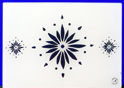 White cutting board with blue flowerburst design. Board displayed on a blue background. Premium glass worktop saver and serving board. A4 size.