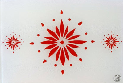 White cutting board with red flowerburst design. Board displayed on a blue background. Premium glass worktop saver and serving board. A4 size.