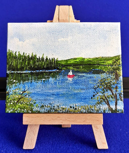 Kielder Sail 3 – Original Mini Gouache Painting with Wooden Easel.
Bring a piece of the dramatic Northumberland wilderness into your home. Kielder Sail is an original, hand-painted gouache artwork capturing a tranquil sailboat gliding across the vast waters of Kielder Reservoir. Complete with its own mini display easel, this charming miniature painting adds a subtle, artistic accent to any desk, shelf, or mantlepiece.
100% Original Art: Signed by the artist—not a print. Unique, one-of-a-kind piece.
