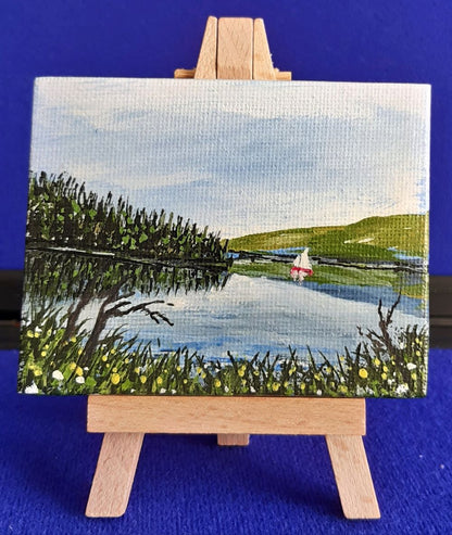 Kielder Sail  1 – Original Mini Gouache Painting with Wooden Easel.
Bring a piece of the dramatic Northumberland wilderness into your home. Kielder Sail is an original, hand-painted gouache artwork capturing a tranquil sailboat gliding across the vast waters of Kielder Reservoir. Complete with its own mini display easel, this charming miniature painting adds a subtle, artistic accent to any desk, shelf, or mantlepiece.
100% Original Art: Signed by the artist—not a print. Unique, one-of-a-kind piece.