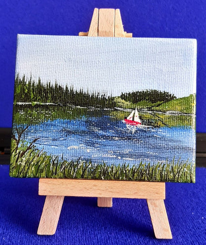 Kielder Sail 2 – Original Mini Gouache Painting with Wooden Easel.
Bring a piece of the dramatic Northumberland wilderness into your home. Kielder Sail is an original, hand-painted gouache artwork capturing a tranquil sailboat gliding across the vast waters of Kielder Reservoir. Complete with its own mini display easel, this charming miniature painting adds a subtle, artistic accent to any desk, shelf, or mantlepiece.
100% Original Art: Signed by the artist—not a print. Unique, one-of-a-kind piece.